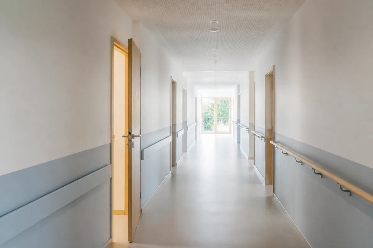 Couloir lumineux d’un établissement médico-social avec porte entrouverte